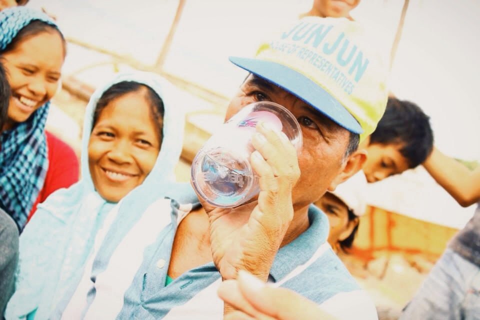 A Filipino man drinks water that has been filtered by a water filtration unit distributed by Convoy of Hope in response to Typhoon Haiyan.